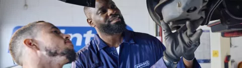 Point S technician inspecting a worn shock absorber on a car