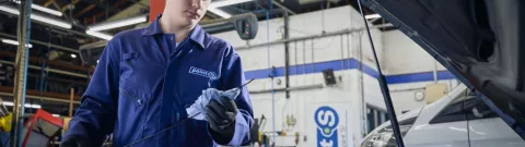 A Point S technician carrying out a car service, checking the engine oil and fluid levels