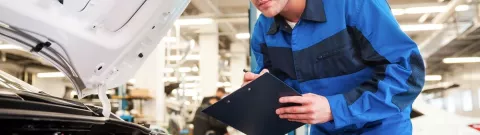 An MOT tester checking a car engine during an MOT test