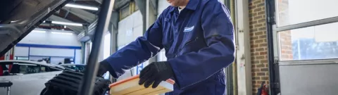 A Point S technician performing an air filter change during a car service