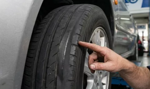 Point S technician inspecting uneven tyre wear on a car tyre