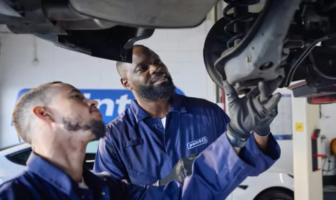 Point S technician inspecting a worn shock absorber on a car