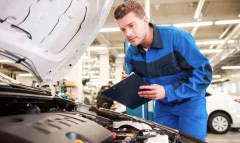 An MOT tester checking a car engine during an MOT test