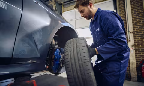 A Point S technician holding a wheel to check brake pads and discs on a car in Point S UK centre