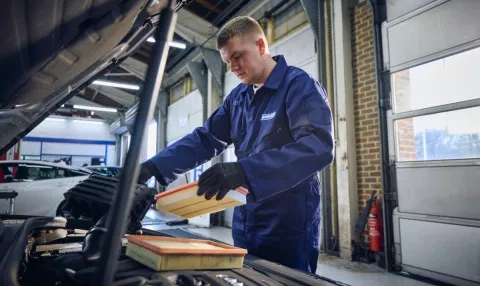 A Point S technician performing an air filter change during a car service