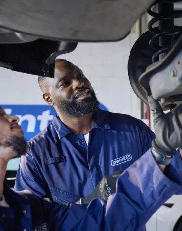 Point S technician inspecting a worn shock absorber on a car