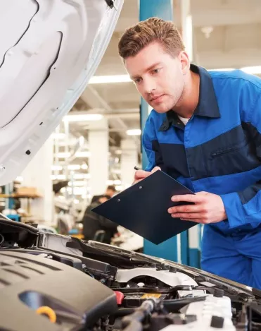 An MOT tester checking a car engine during an MOT test