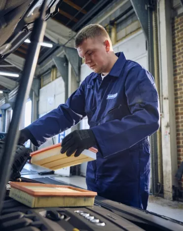 A Point S technician performing an air filter change during a car service